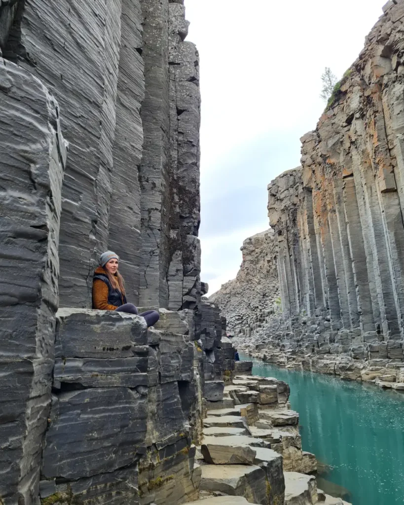 Maríanna seated among the basalt columns of Stuðlagil canyon, east Iceland