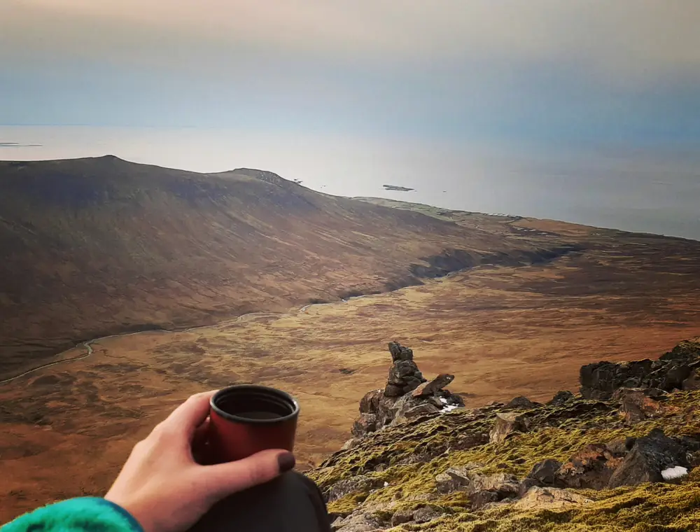 Looking out over the Icelandic coast from a mountain top, coffee in hand